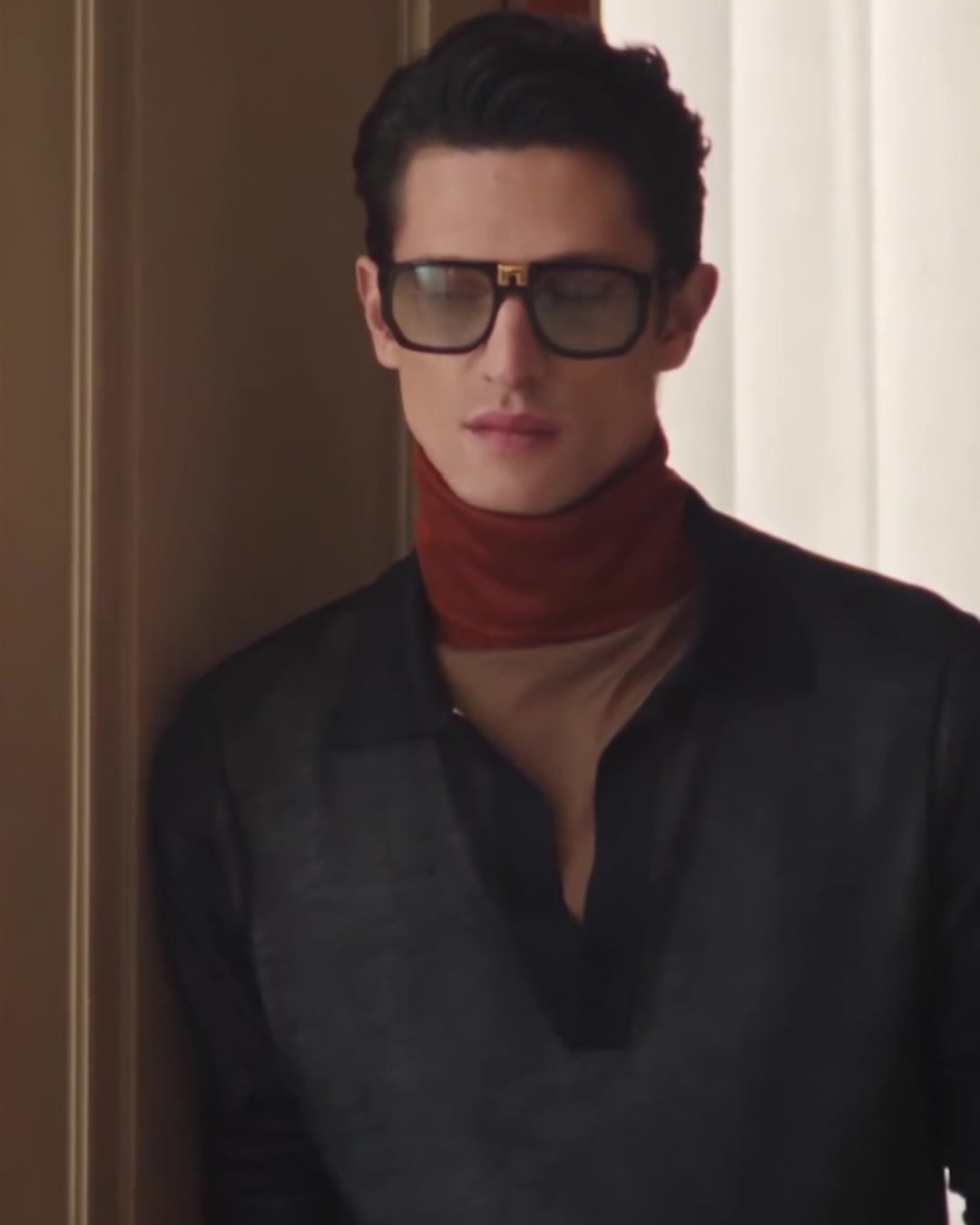 Close-up of the man in black frames by the window