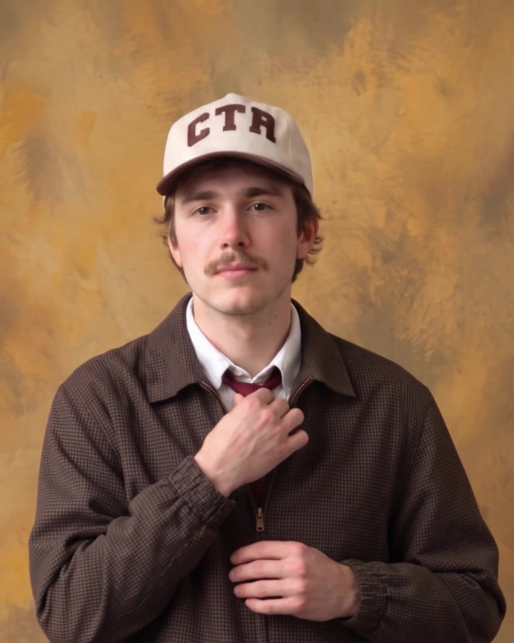 Close portrait on a mottled backdrop, adjusting the tie